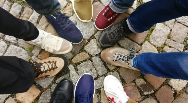 Circle of sneakers on cobblestone pavement representing diversity and urban fashion.