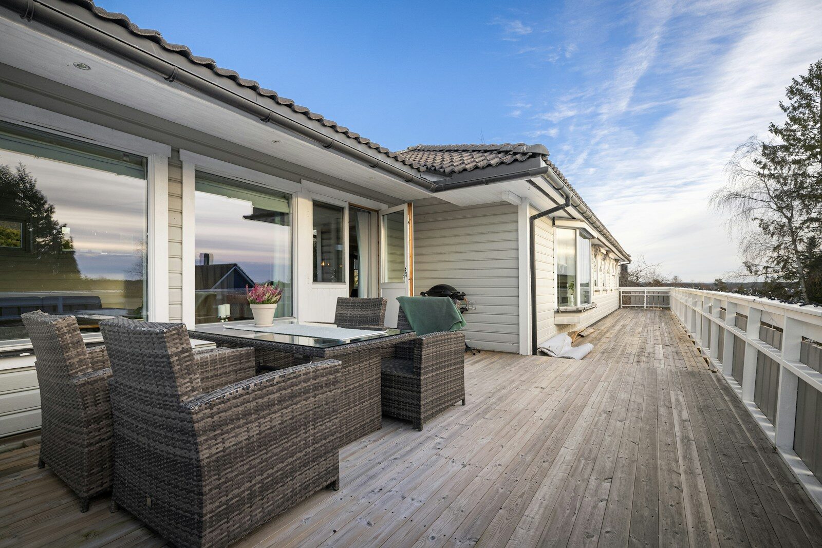 A wooden deck with wicker furniture and a view of the ocean