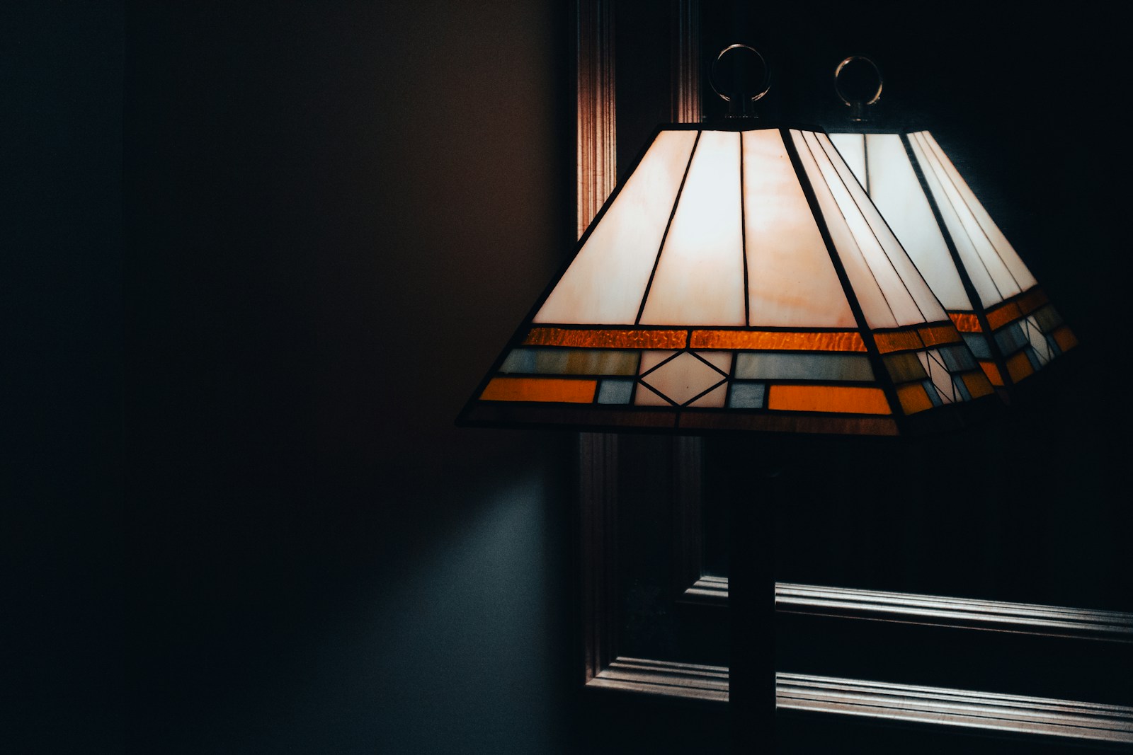 a stained glass lamp hanging from the side of a wall